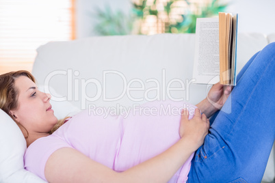 Pregnant woman reading a book on couch