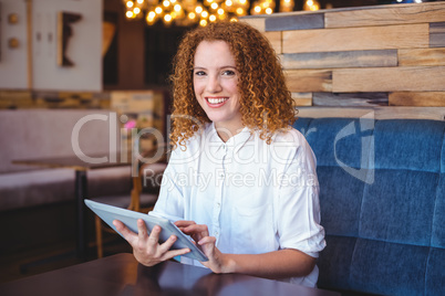 Pretty girl using a small tablet at table