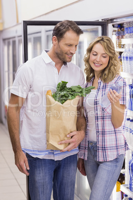 Smiling casual couple looking at water bottle