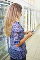Pretty blonde woman buying frozen products and texting