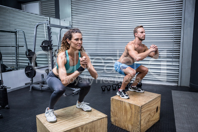 Muscular couple doing jumping squats