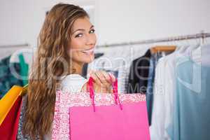 Portrait of smiling woman holding shopping bags and looking at c