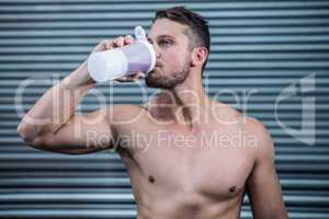 Muscular man drinking protein cocktail