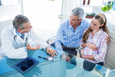 Pregnant woman and her husband discussing with doctor