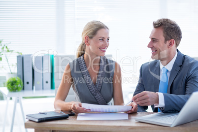 Happy colleagues working together on laptop and folder