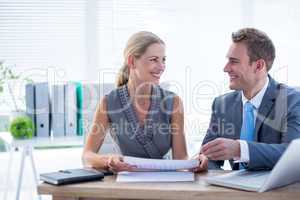 Happy colleagues working together on laptop and folder