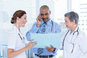 Concentrated doctor showing file to his colleagues while calling