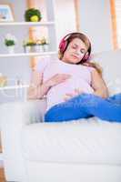 Pregnant woman listening music and touching her belly