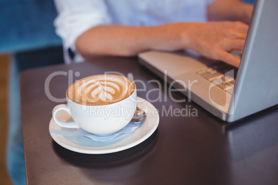 Pretty girl having coffee using laptop