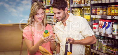 Smiling bright couple buying food products with shopping basket