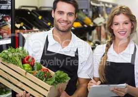 Portrait of two colleagues holding a box with fresh vegetables a