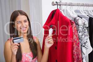 Portrait of smiling woman looking at red coat and holding credit
