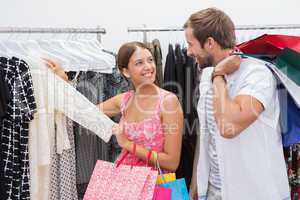 Smiling couple with shopping bags looking at clothes