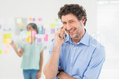 Businessman having phone call while his colleague posing