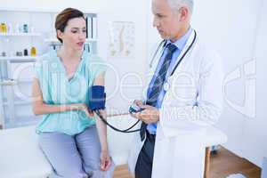 Doctor checking blood pressure of a young woman