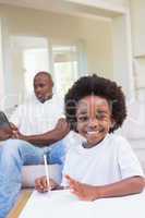 Smiling little boy writing on table