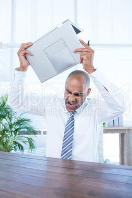 Irritated businessman about to break his laptop
