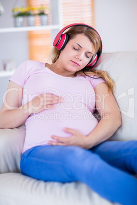 Pregnant woman listening music and touching her belly