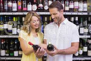 Smiling casual couple looking at wine bottle