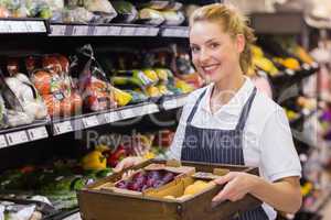 Portrait of a smiling blonde worker holding a box with vegetable