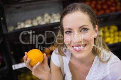 Smiling pretty blonde woman buying oranges