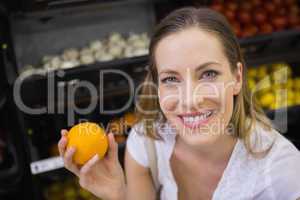 Smiling pretty blonde woman buying oranges