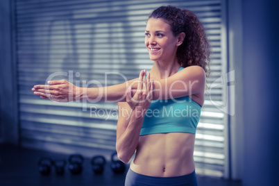 Smiling muscular woman stretching arms