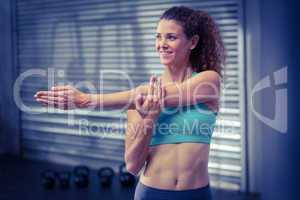 Smiling muscular woman stretching arms
