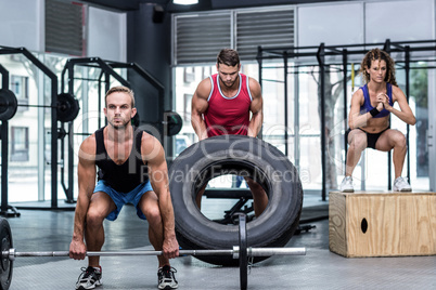 Serious three muscular people lifting and jumping