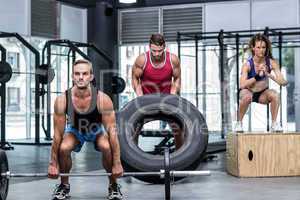 Serious three muscular people lifting and jumping