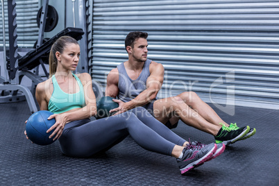 Muscular couple doing abdominal ball exercise