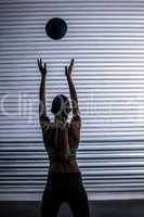 Muscular woman throwing ball in the air