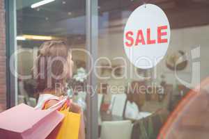 Smiling woman with shopping bags looking at window