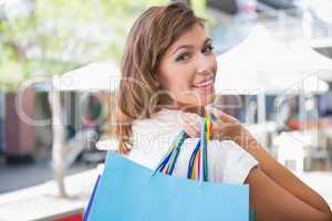 Portrait of smiling woman holding shopping bag and looking over
