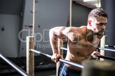 Muscular man exercising on parallel bars