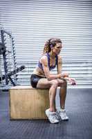 Focused muscular woman sitting on a box