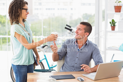 Businesswoman handing a mug of coffee to his colleague