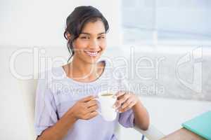 Casual businesswoman having a coffee at desk