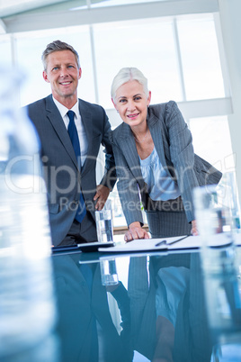 Business people looking at camera behind desk