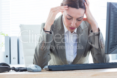 Upset business woman with head in hands in front of computer at