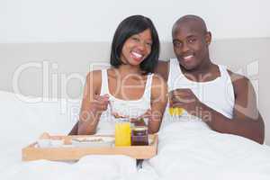 Portrait of a pretty couple taking breakfast in bed together