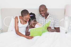 Pretty couple with her daughter reading a green book in bed