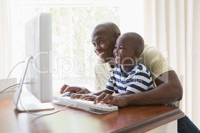 Happy smiling father with his son using computer