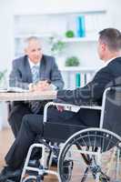 Businessman in wheelchair speaking with colleague