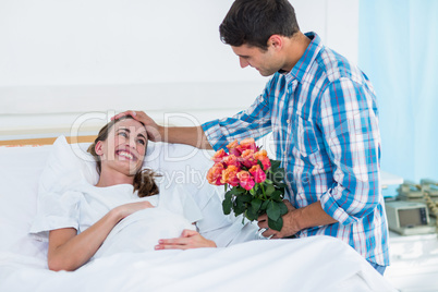 Man offering flowers to pregnant woman in hospital