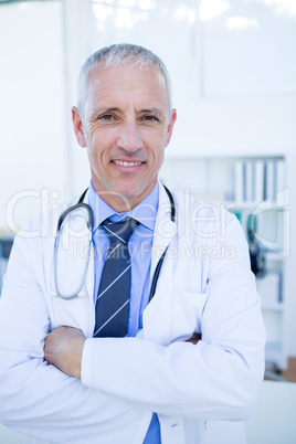Happy male doctor looking at camera with arms crossed