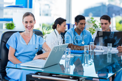 Happy doctor looking at camera while her colleagues looks at Xra