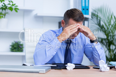 Businessman with severe headache sitting at office desk