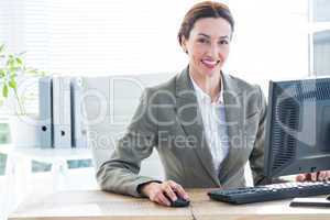 Businesswoman using computer and smiling at camera