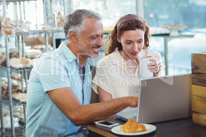 Happy couple pointing something on laptop